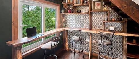 Una cocina acogedora con una mesa de madera, taburetes de bar y un ordenador portátil sobre la encimera.