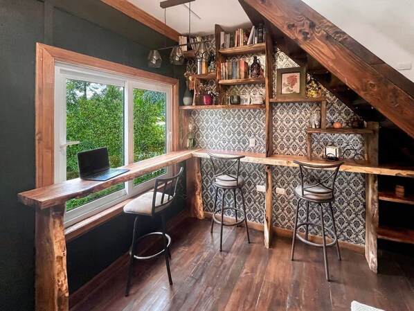 Una cocina acogedora con una mesa de madera, taburetes de bar y un ordenador portátil sobre la encimera.