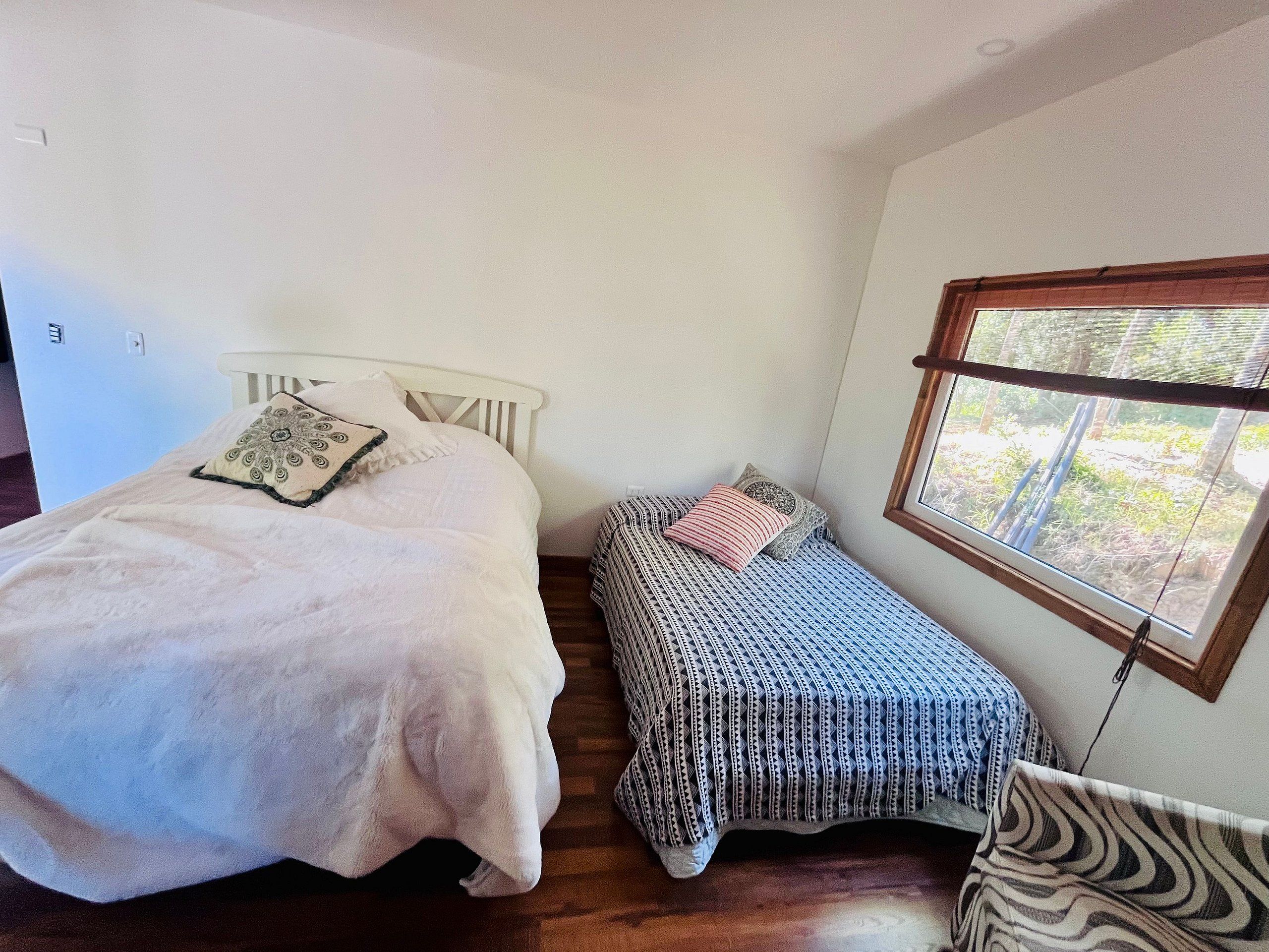 Une chambre avec deux lits, une fenêtre donnant sur un beau paysage et un plancher en bois.