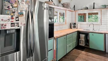 Una cocina con un refrigerador de acero inoxidable, techo de madera y armarios verdes.