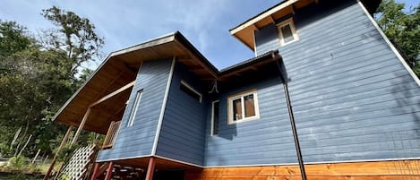 A two-story wooden house with a porch and a small attached structure.