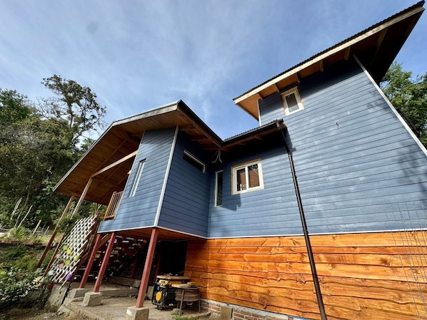 A two-story wooden house with a porch and a small attached structure. - Oceana Suites Lago Panguipulli (Panguipulli)