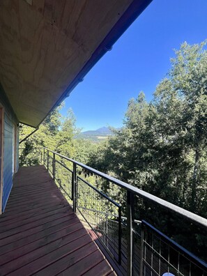 A wooden deck with a metal railing overlooking a forested landscape with mountains in the distance. - Oceana Suites Lago Panguipulli (Panguipulli)