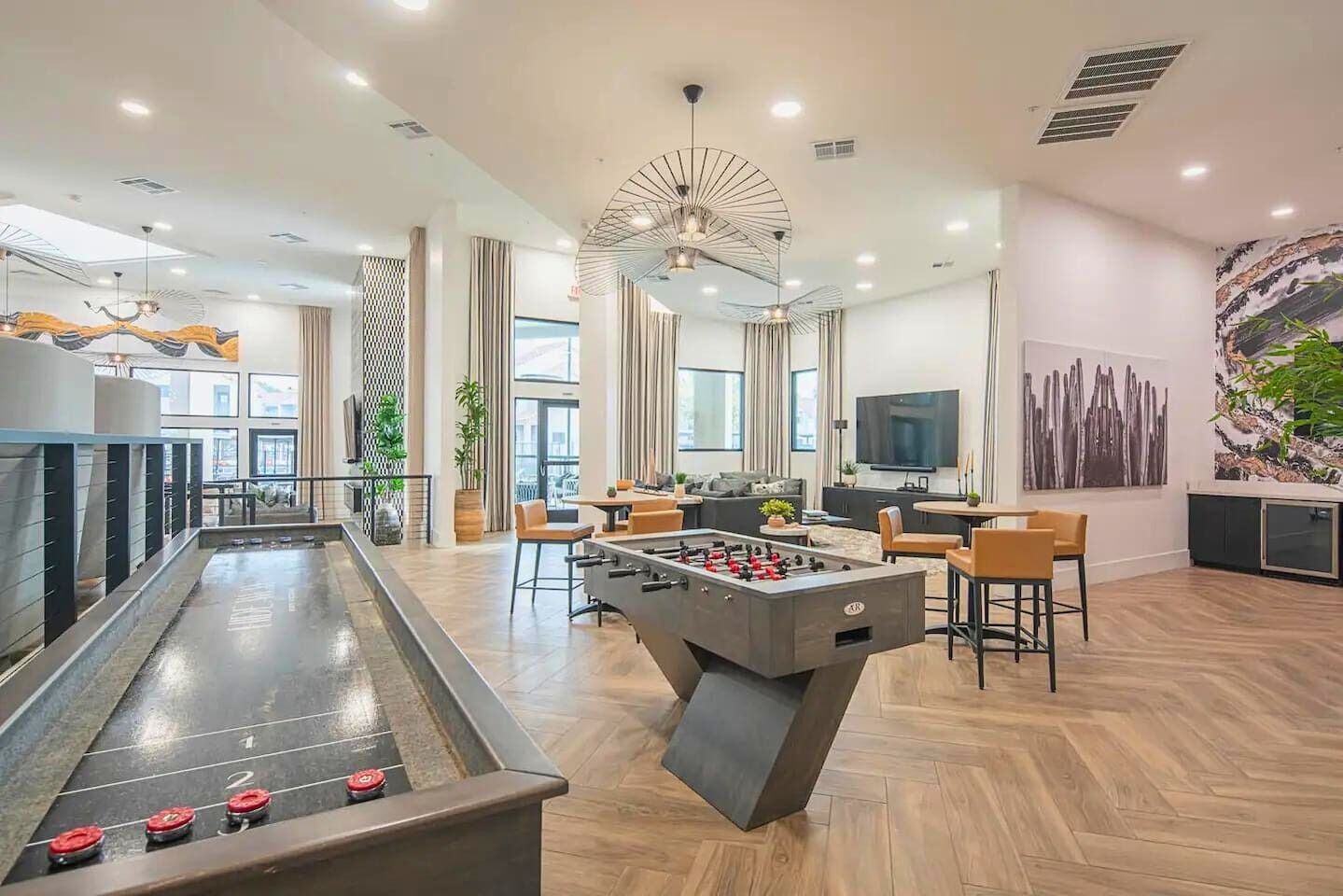 Un espacio interior moderno con mesa de futbolín, zona de estar y mesa de billar.