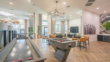 Un espacio interior moderno con mesa de futbolín, zona de estar y mesa de billar.