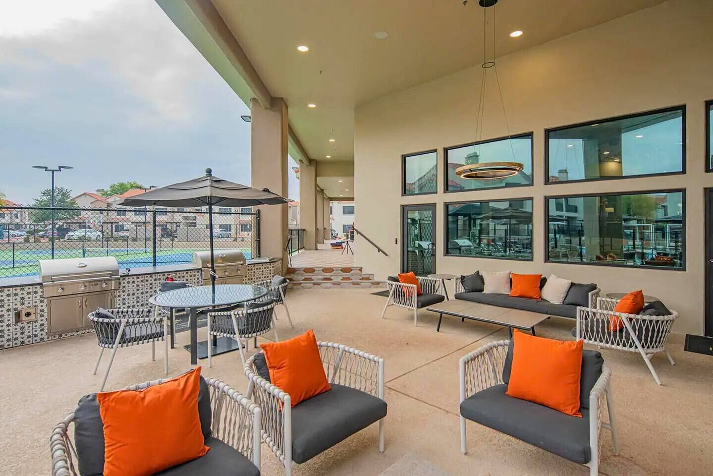 Un patio exterior con mobiliario, una parrilla y vista a una piscina.