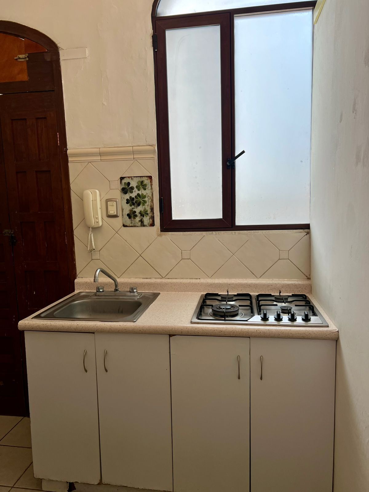 Een keuken met een gasfornuis, een spoelbak en een raam met gezoet glas.