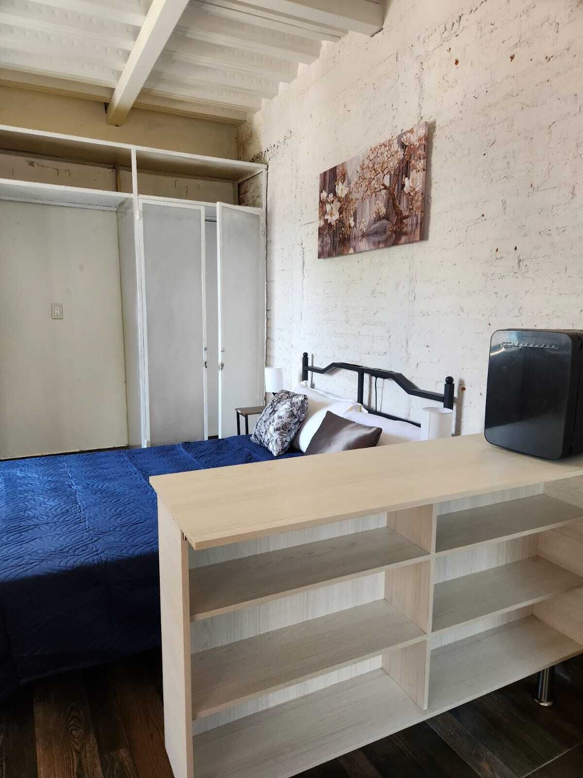 Una camera da letto con un letto, una scrivania, una sedia, una TV e un armadio.