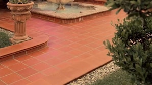 Ein Patio mit mehrstufiger Fontäne, Sitzgelegenheiten im Freien und einer überdachten Struktur.