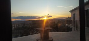 A balcony with a railing, a table, and a view of a sunset over a body of water and distant hills. - Spacious villa ideal for families just a stone's throw from the Verdon (Tavernes)