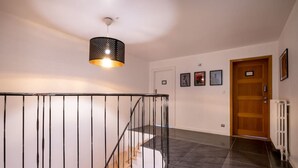 A staircase with a black railing, a wooden door, and a wall-mounted light fixture.