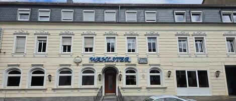 Egy épület, amelynek a homlokzatán egy „WALSTETER” és egy „PARISER UPRIS” feliratú tábla található.