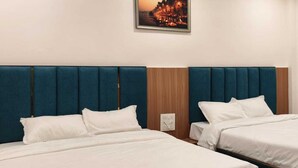 A hotel room with two beds, a wooden headboard, and a nightstand. - Majestic Ganges (Haridwar)