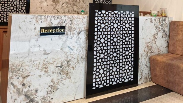 A reception desk with a marble top, a chandelier, a clock, and a patterned wall. - Majestic Ganges (Haridwar)
