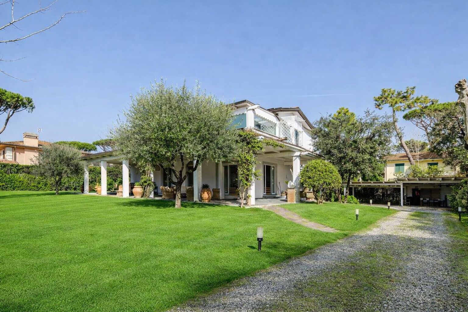 A two-story house with a covered porch, a well-maintained lawn, and a gravel path leading to the entrance.