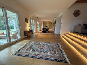 A modern interior with a wooden floor, a patterned rug, a dining area with a table and chairs, and a sofa. - Forte dei Marmi, Italy. Entire Villa with pool, perfect for big families (Forte dei Marmi)