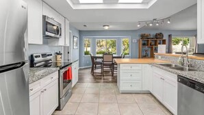 Una cucina moderna con elettrodomestici in acciaio inossidabile, un'area pranzo con tavolo e sedie, e vista all'esterno grazie a ampie finestre.