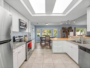 A modern kitchen with stainless steel appliances, a dining area with a table and chairs, and a view of the outdoors through large windows. - Meadowlark Retreat Near Yosemite Private (Ahwahnee)