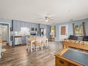 A modern kitchen with grey cabinets, a dining table with chairs, a foosball table, and a ceiling fan. - Meadowlark Retreat Near Yosemite Private (Ahwahnee)
