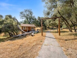 A rustic cabin with a wooden structure, a gravel path leading to it, and surrounding trees. - Meadowlark Retreat Near Yosemite Private (Ahwahnee)