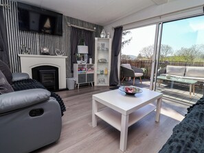 A modern living room with a fireplace, a sofa, a coffee table, and a balcony with outdoor furniture. - Grosvenor 10 (Mold)