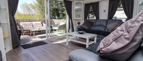 Ein modernes Wohnzimmer mit einer Couch, einem Couchtisch und einer Glastür, die zu einem Außenbereich führt.