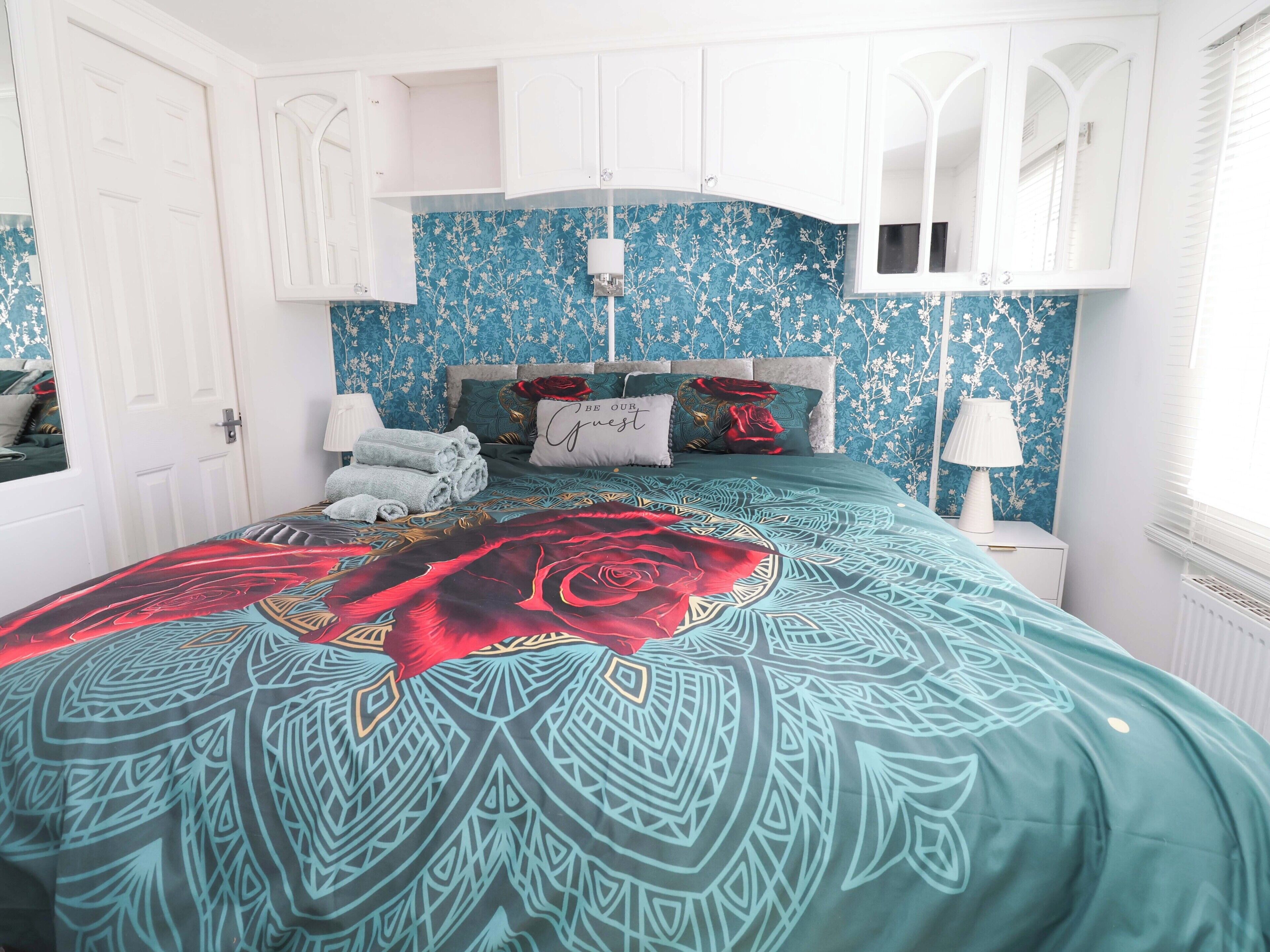 A bedroom with a bed, a nightstand, a lamp, and a window.