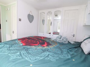 Ein Schlafzimmer mit Bett, Spiegel, Tür und Wand mit Herz-Dekoration.