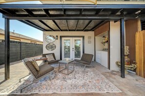 Un patio techado con zona de estar, una mesa pequeña y una alfombra estampada.
