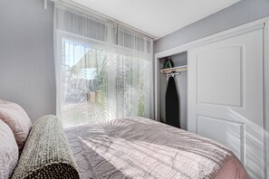 A bedroom with a large window, a bed with a patterned bedspread, a bedside table, and a wardrobe. - 1BR Casita, Central Location + Private Bkyd + Free Uber Airport Pickup (Las Vegas)