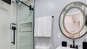 A bathroom with a glass shower enclosure, a toilet, a sink with a mirror, and a towel hanging on the wall. - 1BR Casita, Central Location + Private Bkyd + Free Uber Airport Pickup (Las Vegas)