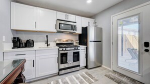 A modern kitchen with white cabinets, a stainless steel refrigerator, a microwave, a stove, and a coffee maker. - 1BR Casita, Central Location + Private Bkyd + Free Uber Airport Pickup (Las Vegas)