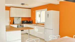 Uma cozinha moderna com armários brancos, bancada de madeira e uma área de refeições com mesa e cadeiras.