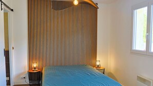 Quarto com cama, duas luminárias de cabeceira, uma janela e um radiador.