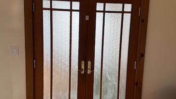 Puerta doble de madera con paneles de vidrio satinado y un tirador.