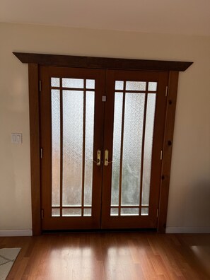 Puerta doble de madera con paneles de vidrio satinado y un tirador.