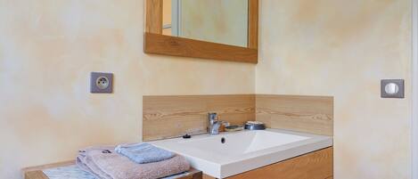 A bathroom with a wooden vanity, a sink, a mirror, and a towel.