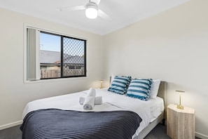 Un dormitorio con cama, ventana con vista, ventilador de techo y lámparas de noche.
