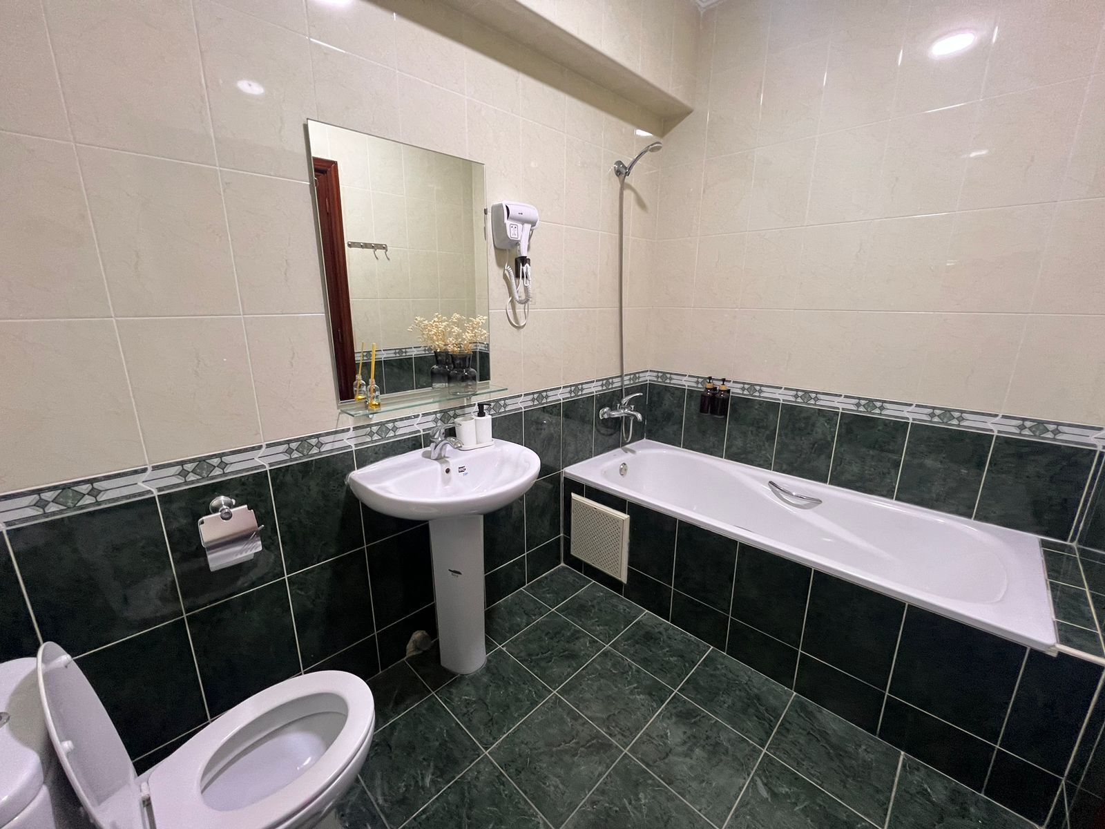 Een badkamer met een witte wastafel, toilet, douche en spiegel.