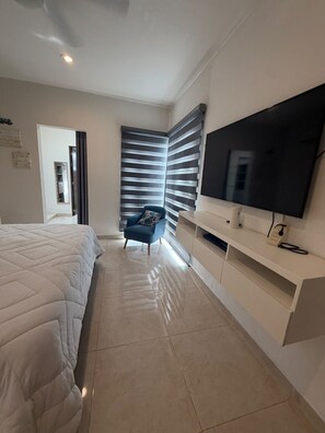 A modern bedroom with a bed, a TV, a chair, and a sliding door.
