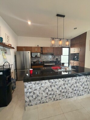 A modern kitchen with a central island, stainless steel appliances, and geometric patterned backsplash.