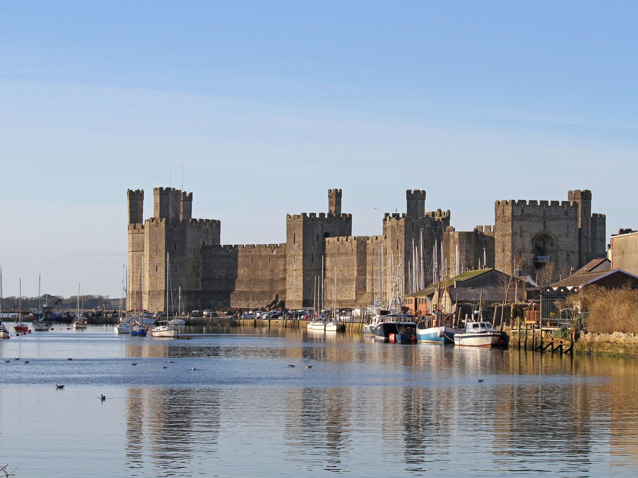 A historic castle with a moat, surrounded by a marina with boats.