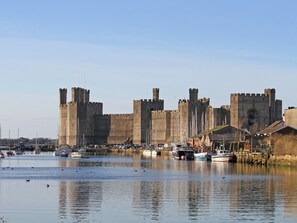 A historic castle with a moat, surrounded by a marina with boats. - Trwyn Cam (Caernarfon)