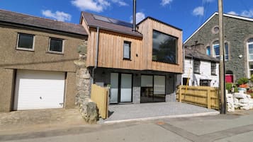 A modern two-story house with a garage, large windows, and a chimney.