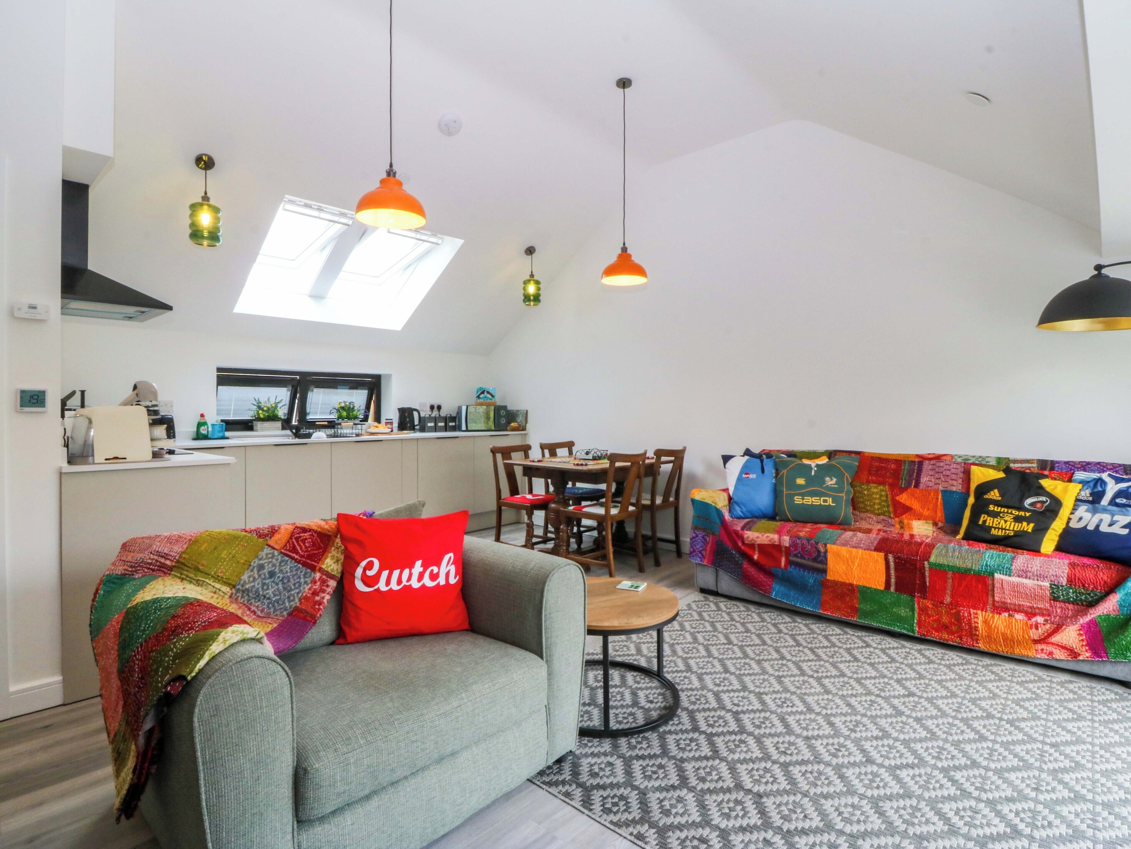 A modern living space with a sofa, a dining table, and a kitchen area.
