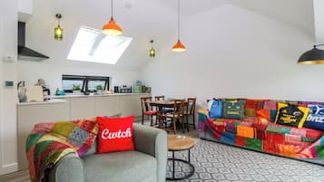 A modern living space with a sofa, a dining table, and a kitchen area.