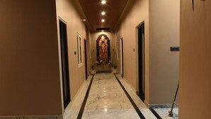 A hallway with a marble floor, doors on either side, and a central decorative element. - Aadvik Residency (Faizabad)