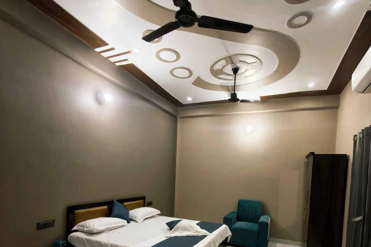 A modern bedroom with a bed, a ceiling fan, a small seating area, and a wardrobe.
