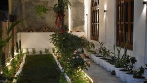 A courtyard with a garden, potted plants, and a stone wall. - Aadvik Residency (Faizabad)