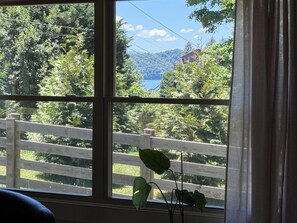A window with a view of a wooden fence, greenery, and a distant mountain. - SoHo-Lakeside Retreat (Abingdon)